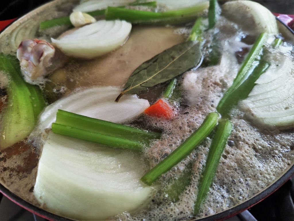 homemade chicken stock with scum rising to the top